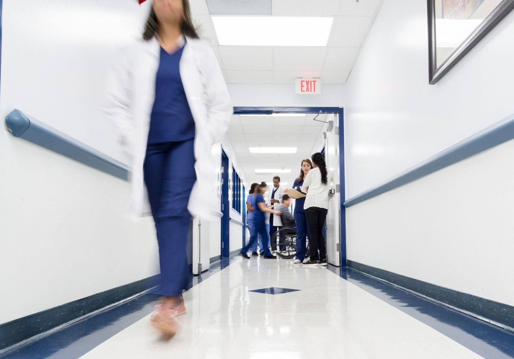 Medical staff walk through or aid patients in a hospital hallway. Image from Canva
