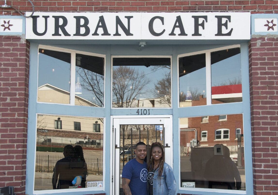 A man and woman standing outside a restaurant.
