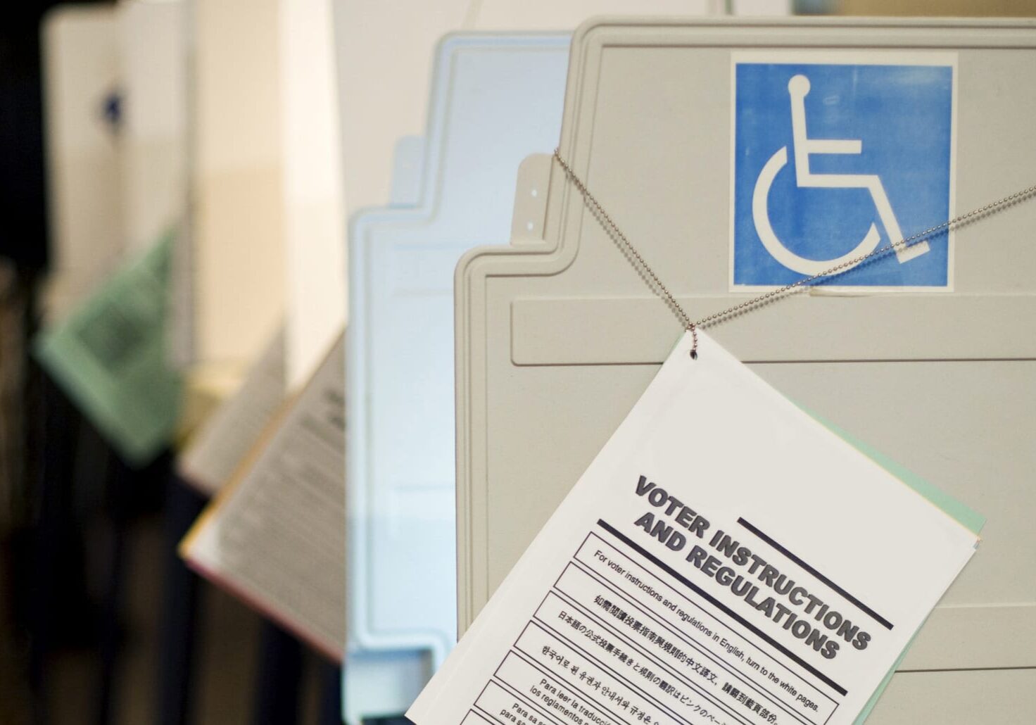 Photo of voting booth with handicap symbol and "Voter Instructions and Regulations" book