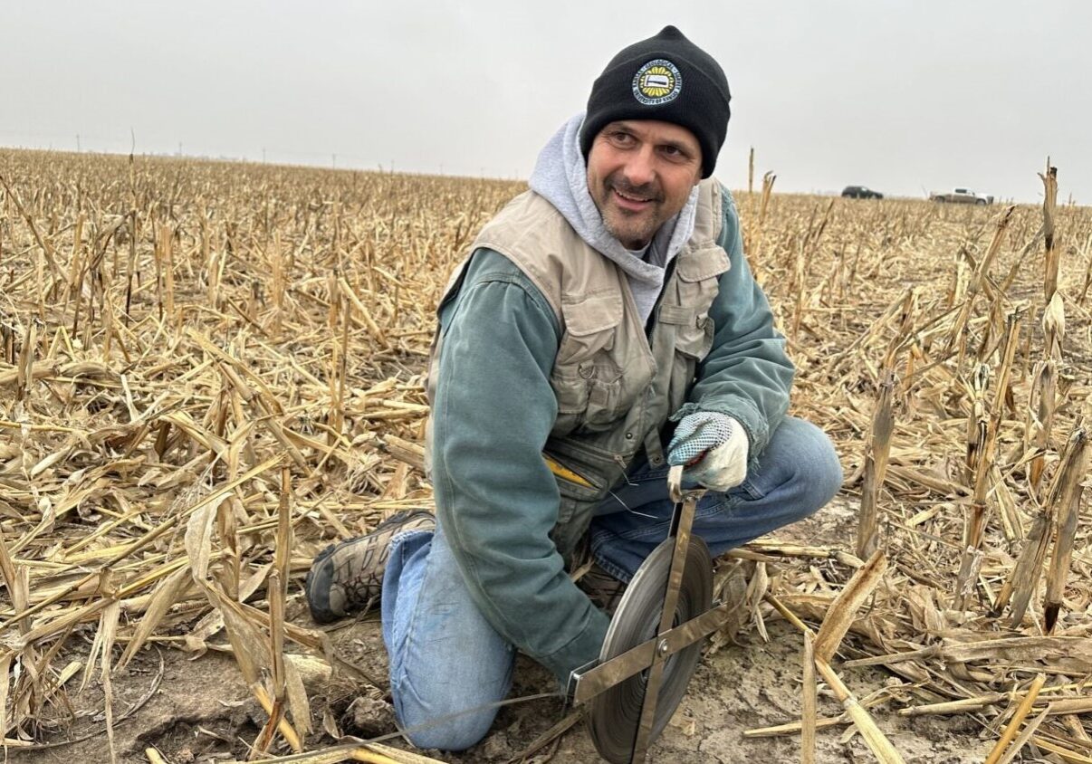 Brownie Wilson kneels next to a decommissioned irrigation well outside Moscow, Kansas.