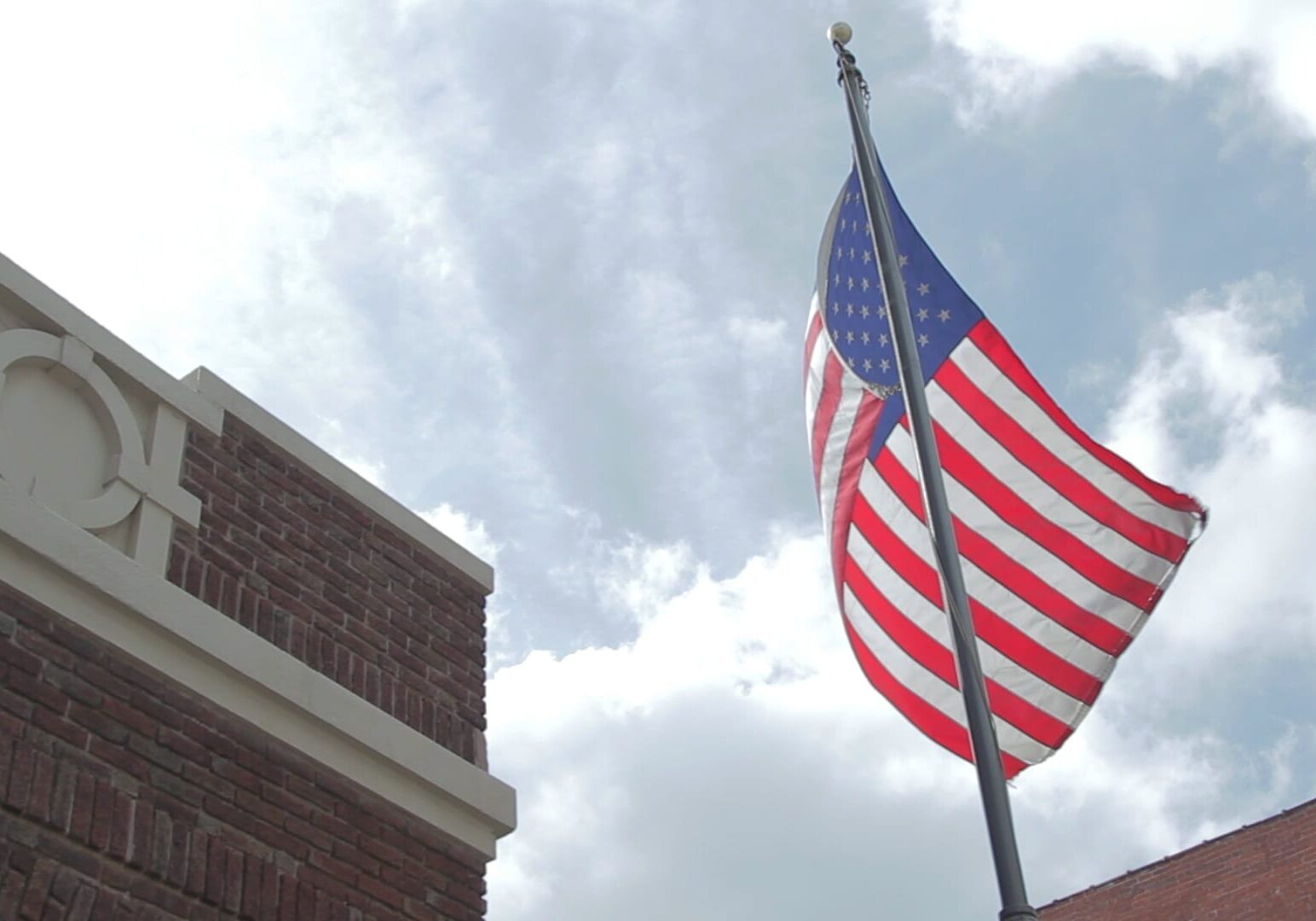 Image of American flag waving in front of brick building