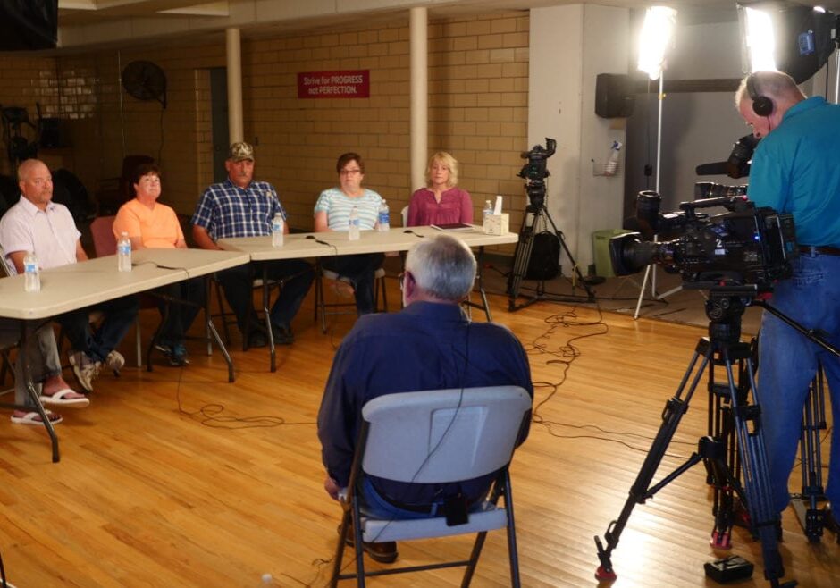 A reporter and videographers talking to seated family members