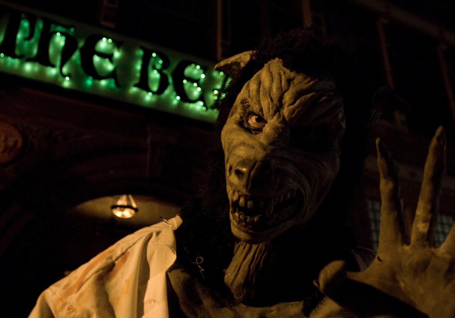 A beast-like creature waves at the camera in front of The Beast Haunted House.