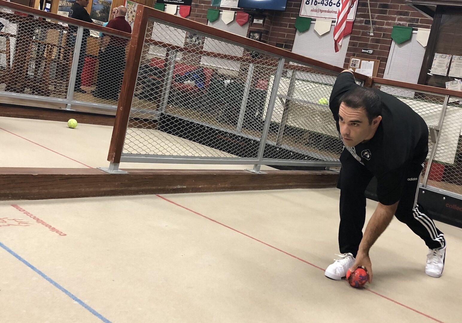 A man readies to roll his bocce ball.