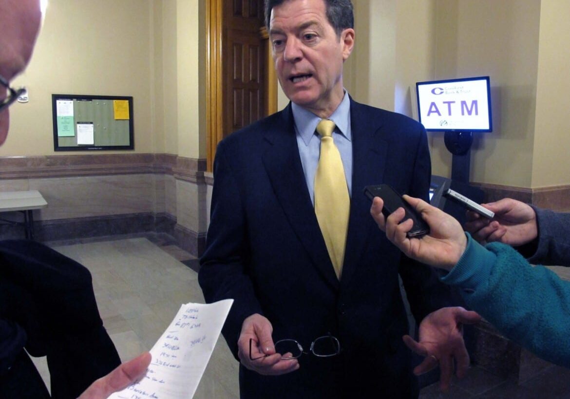 Kansas Gov. Sam Brownback discusses tax and budget issues with reporters, Thursday, March 28, 2013, at the Statehouse in Topeka, Kan. Brownback is defending his proposal to cancel a scheduled drop in the state sales tax to stabilize the budget while pursuing income tax cuts. (AP Photo/John Hanna)