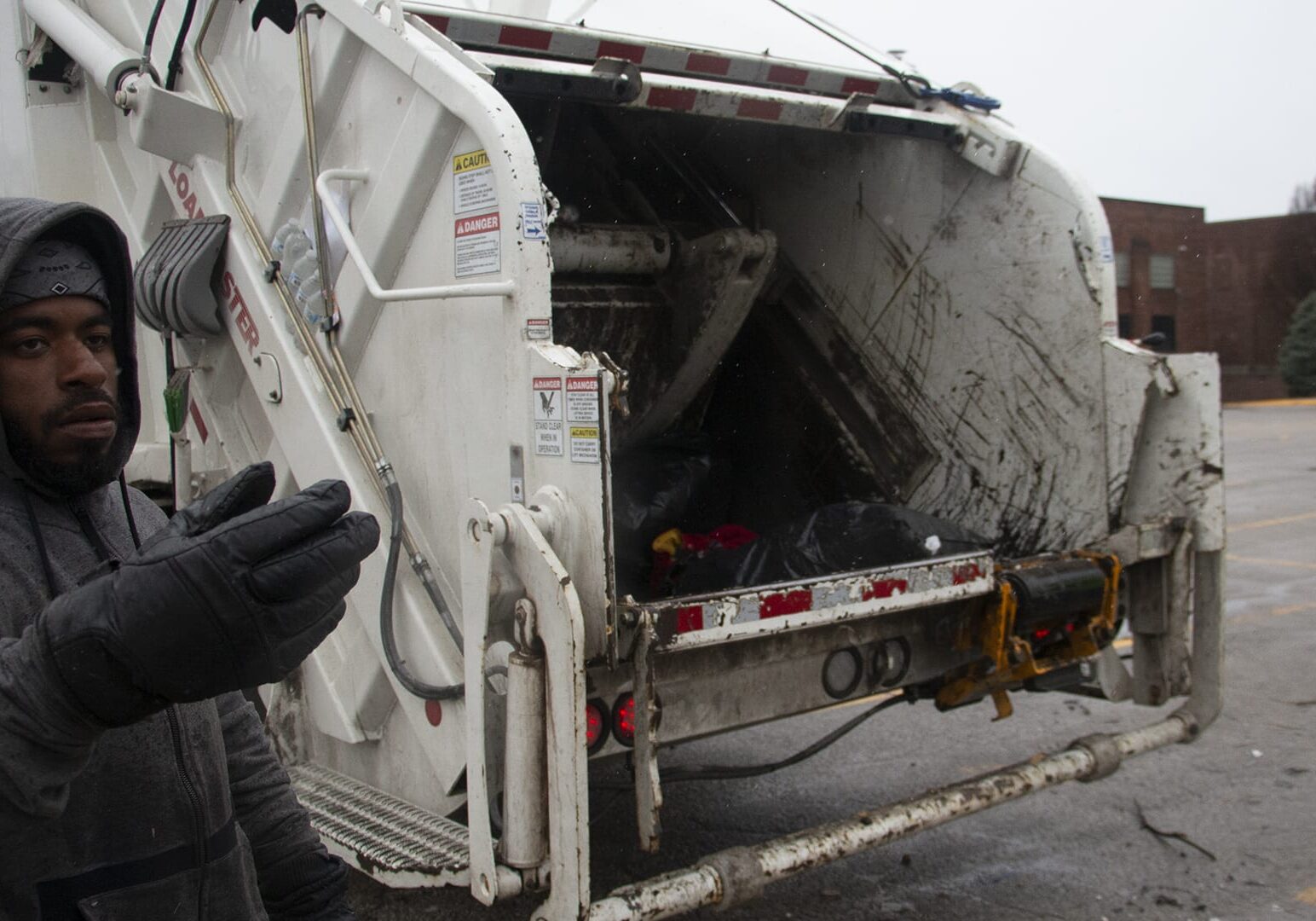 worker guiding motorist to trash truck