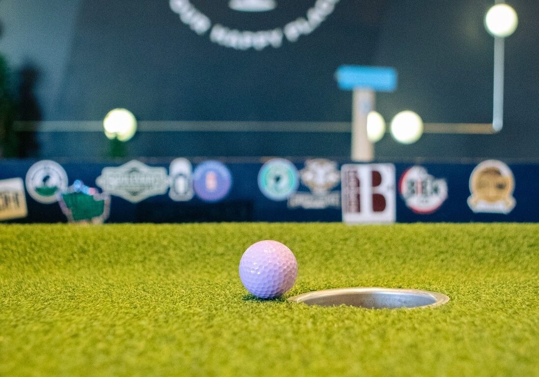 A golf ball near a hole on a mini golf course