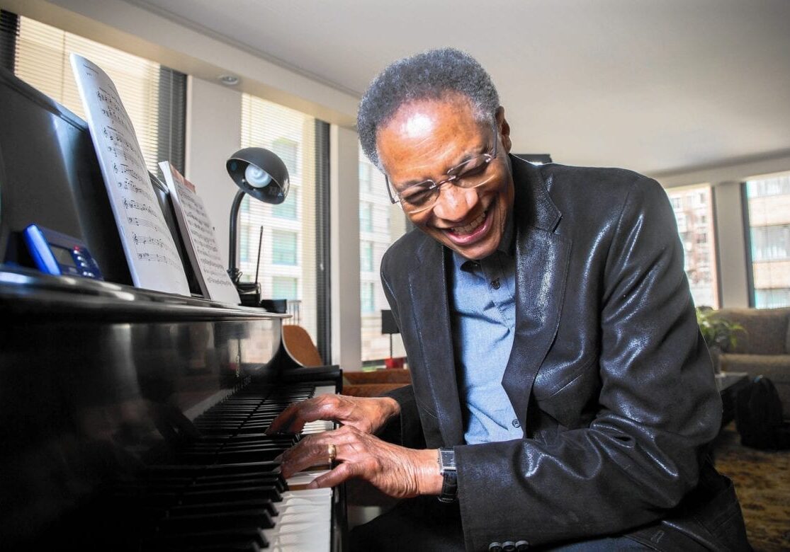 Ramsey Lewis plays the piano laughing.