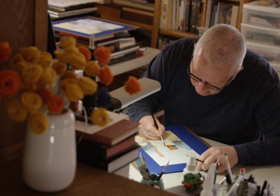 A man painting with watercolors at his desk