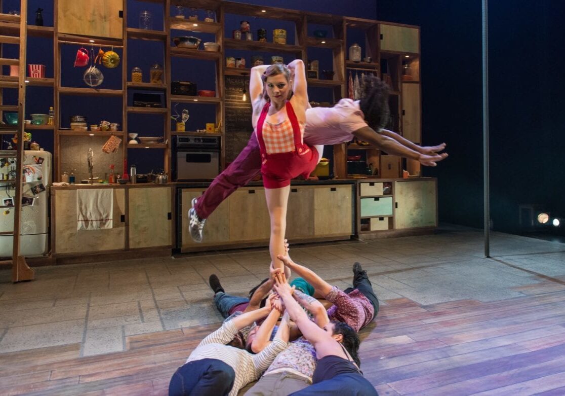 A woman being suspended in the air by other performers.