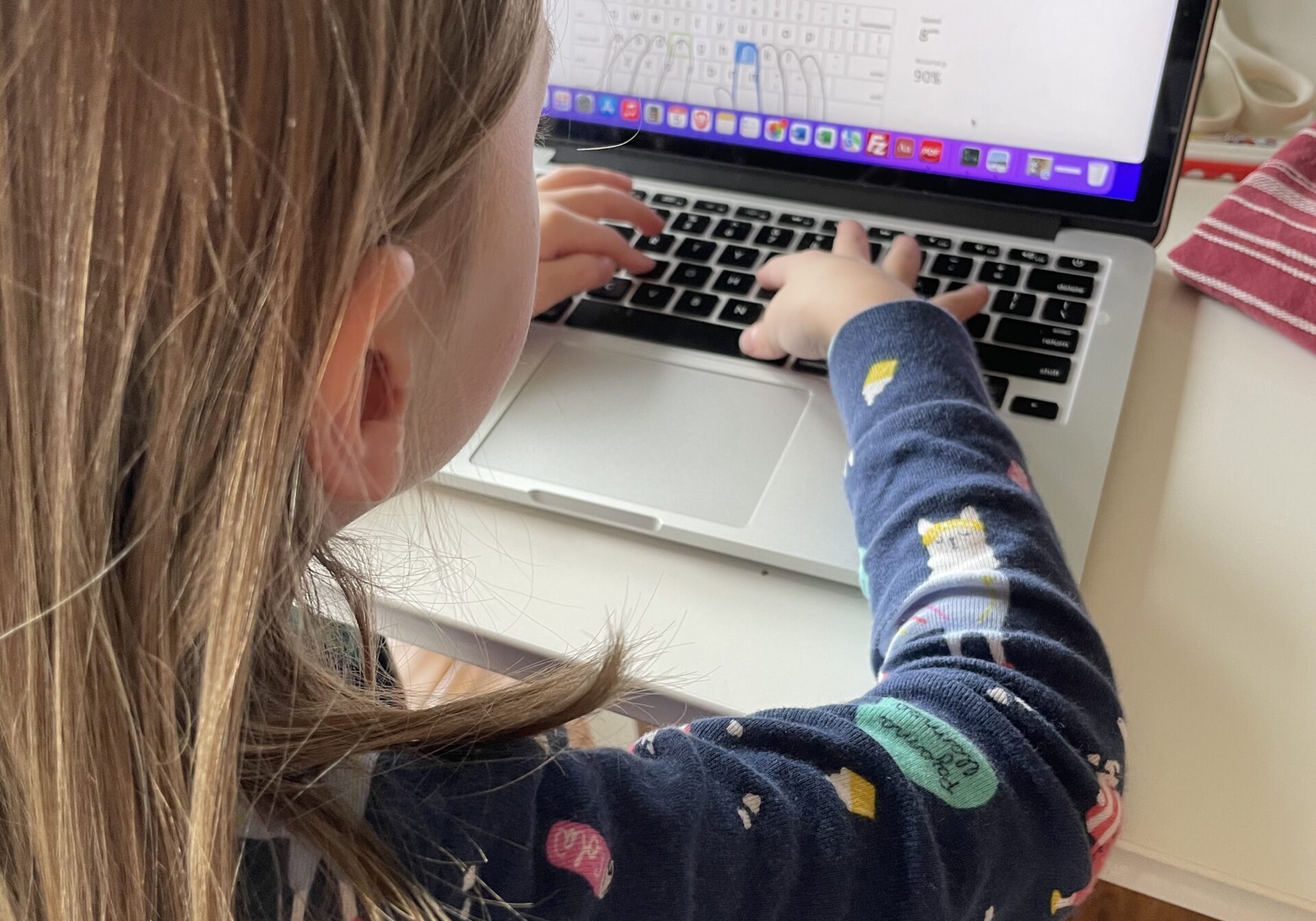 Young girl sits at a laptop practicing her typing skills.