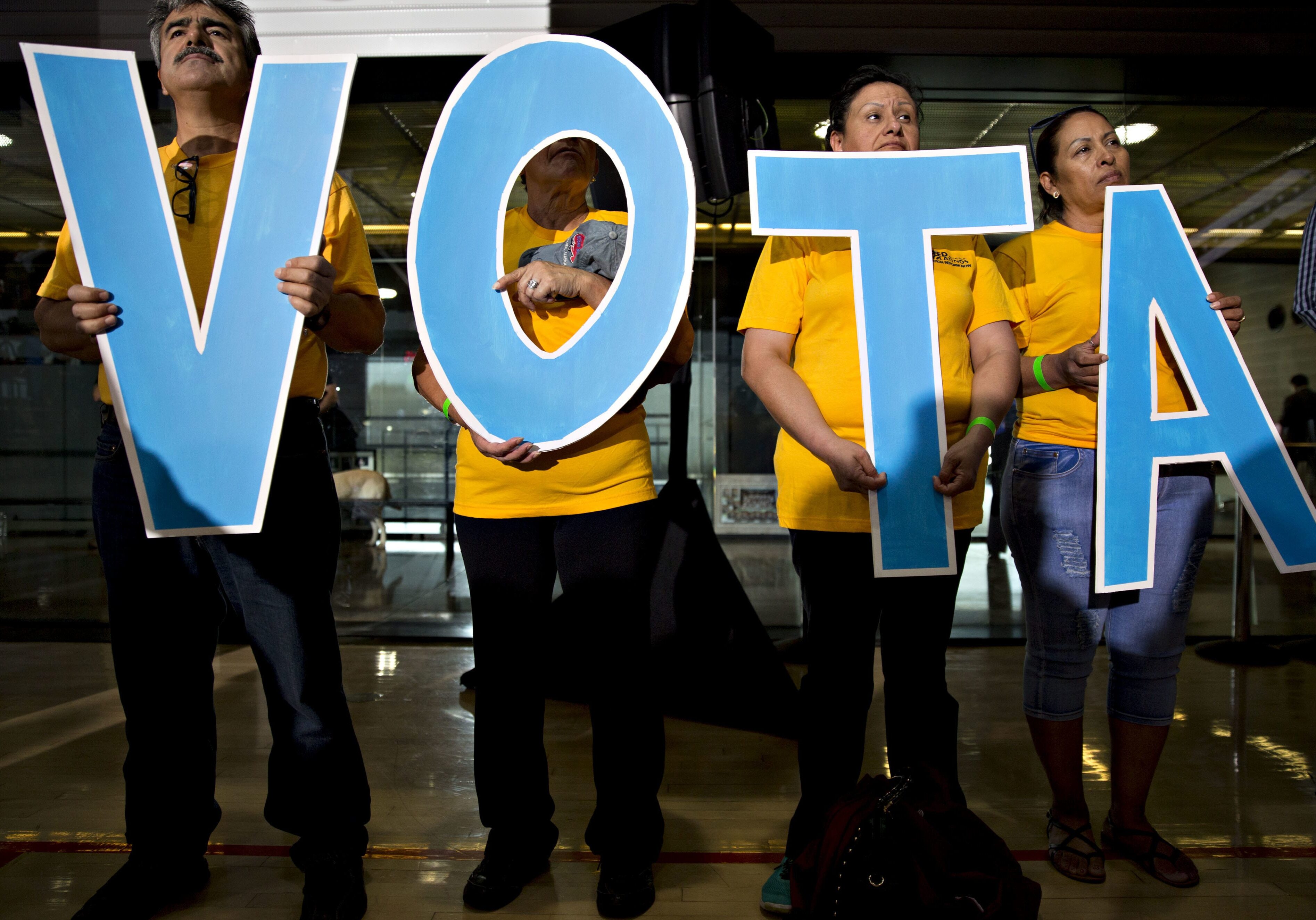 Attendees hold letters reading "vote" in Spanish during a campaign event with Tim Kaine.