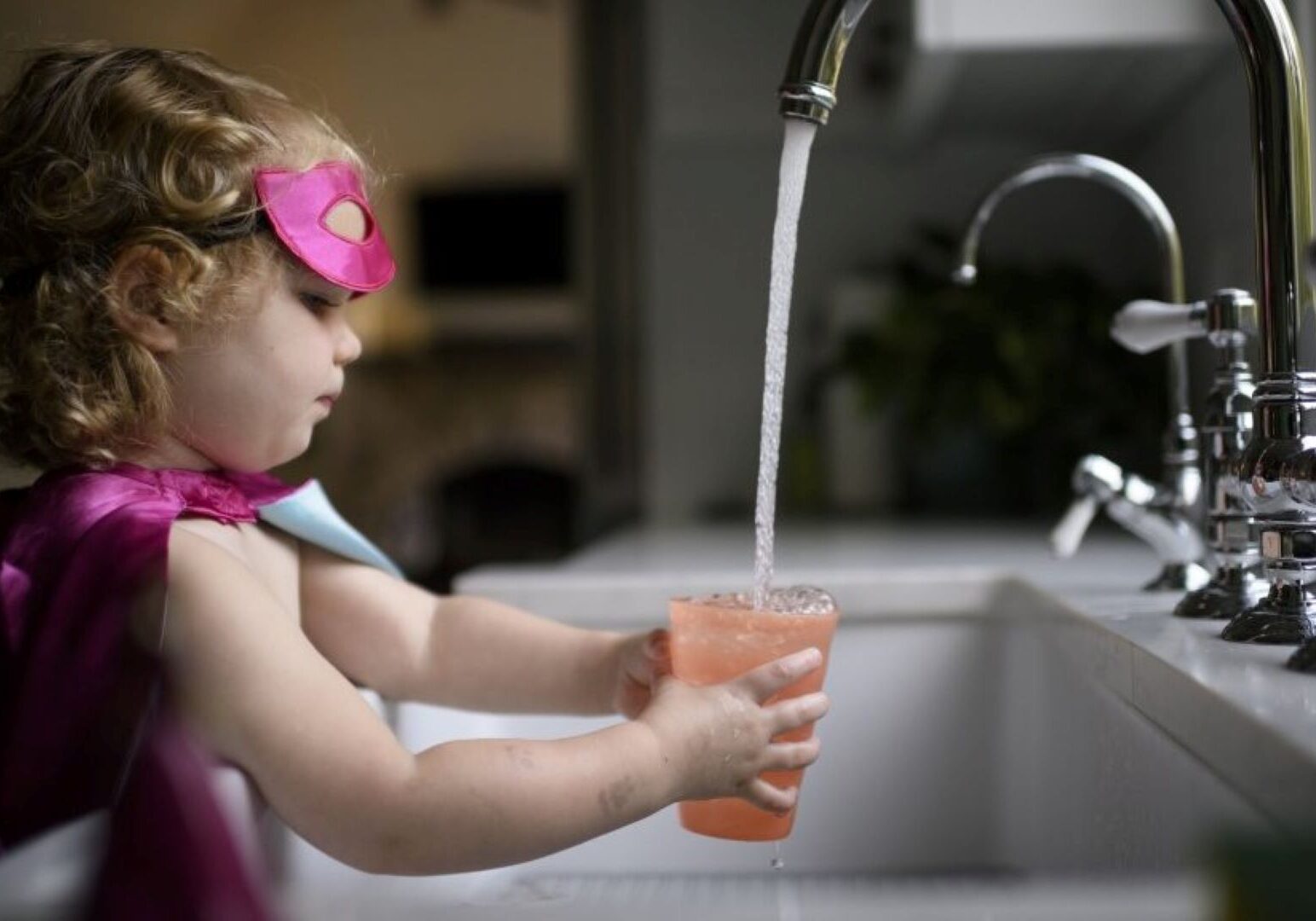 Girl getting water at a sink.