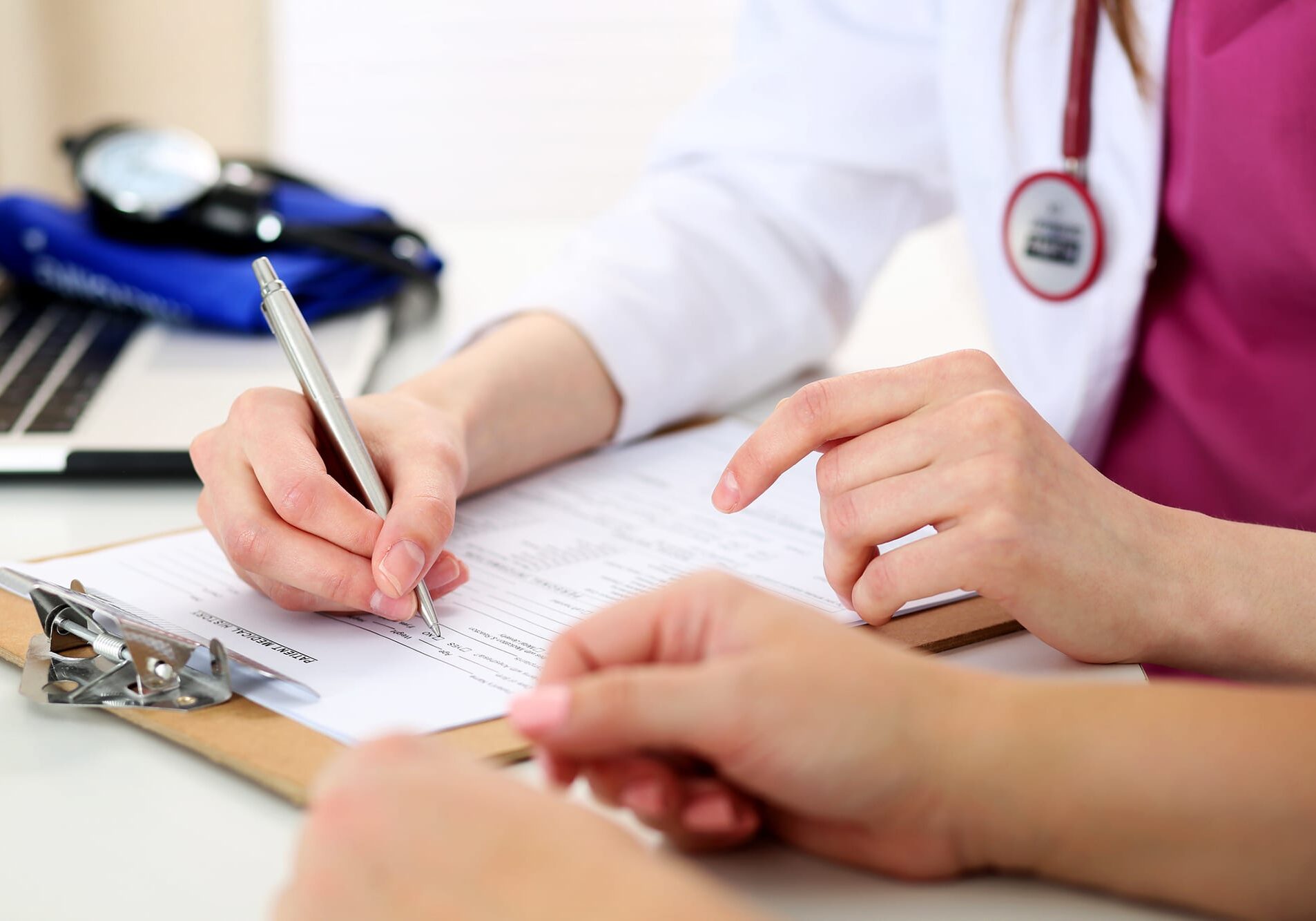 A doctor writing on a medical chart.