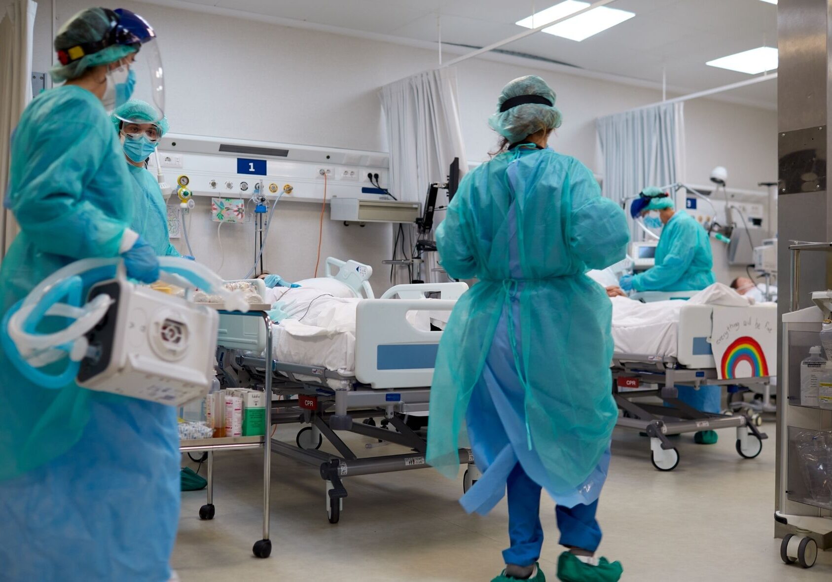 Hospital staff in Personal Protective Equipment such as robes, gloves and masks, treat a patient. This image accompanies our prompt that invites you, the public, to ask questions you want answered about health care.