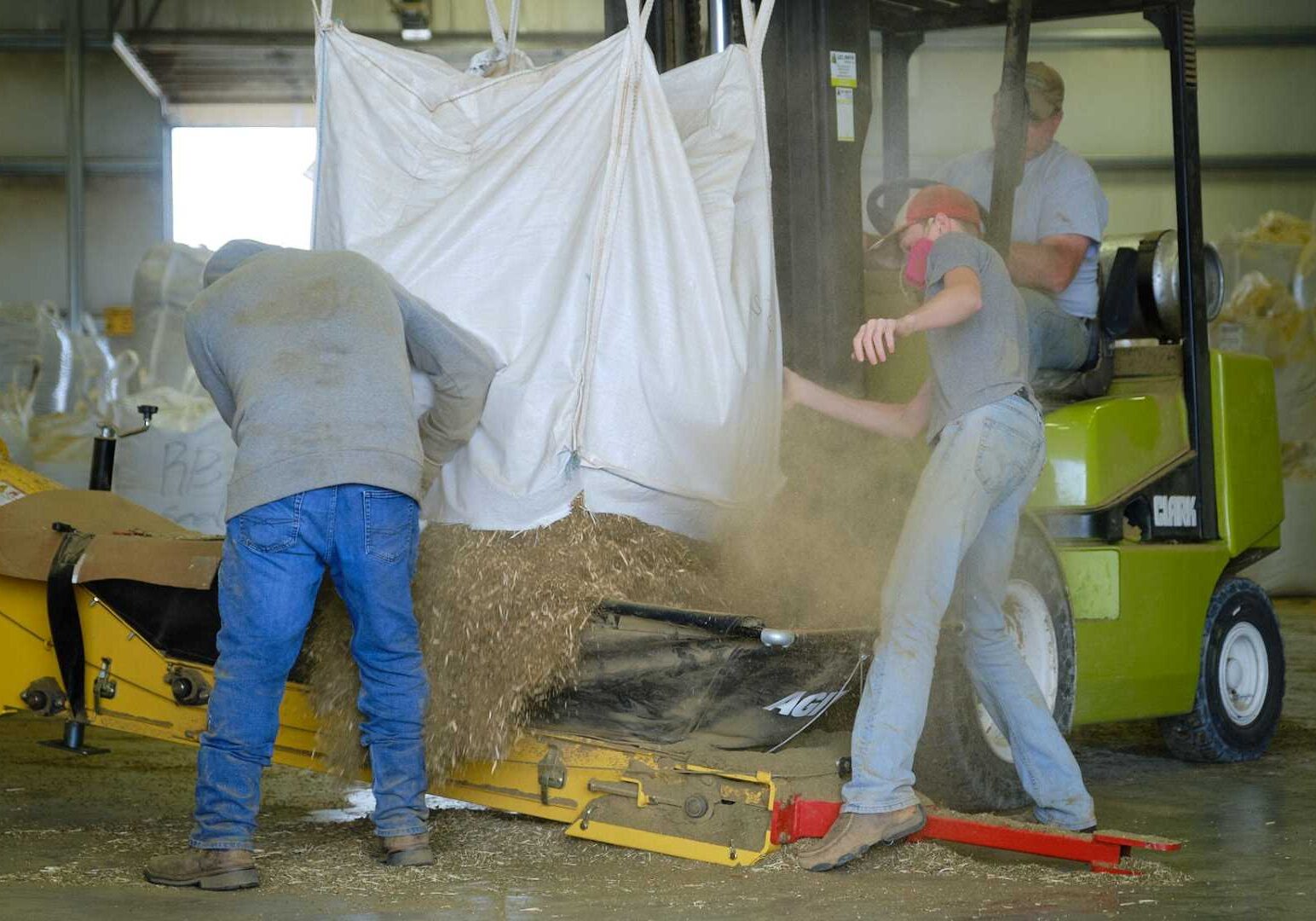 Workers at Shining Star Hemp Co. load a bag of hemp biomass into the processor.