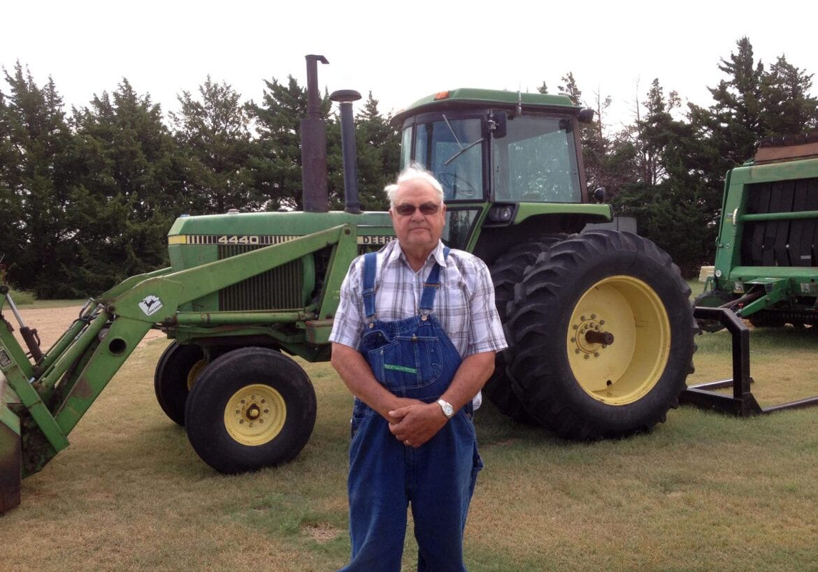 A man standing in front of his farm equipment.