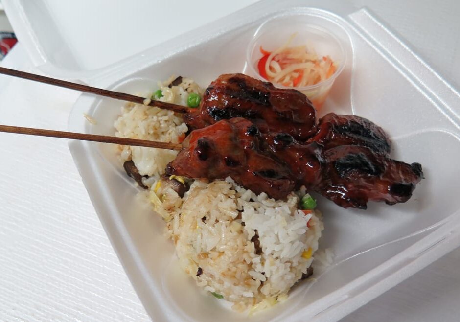 A pair of pork skewers over rice.