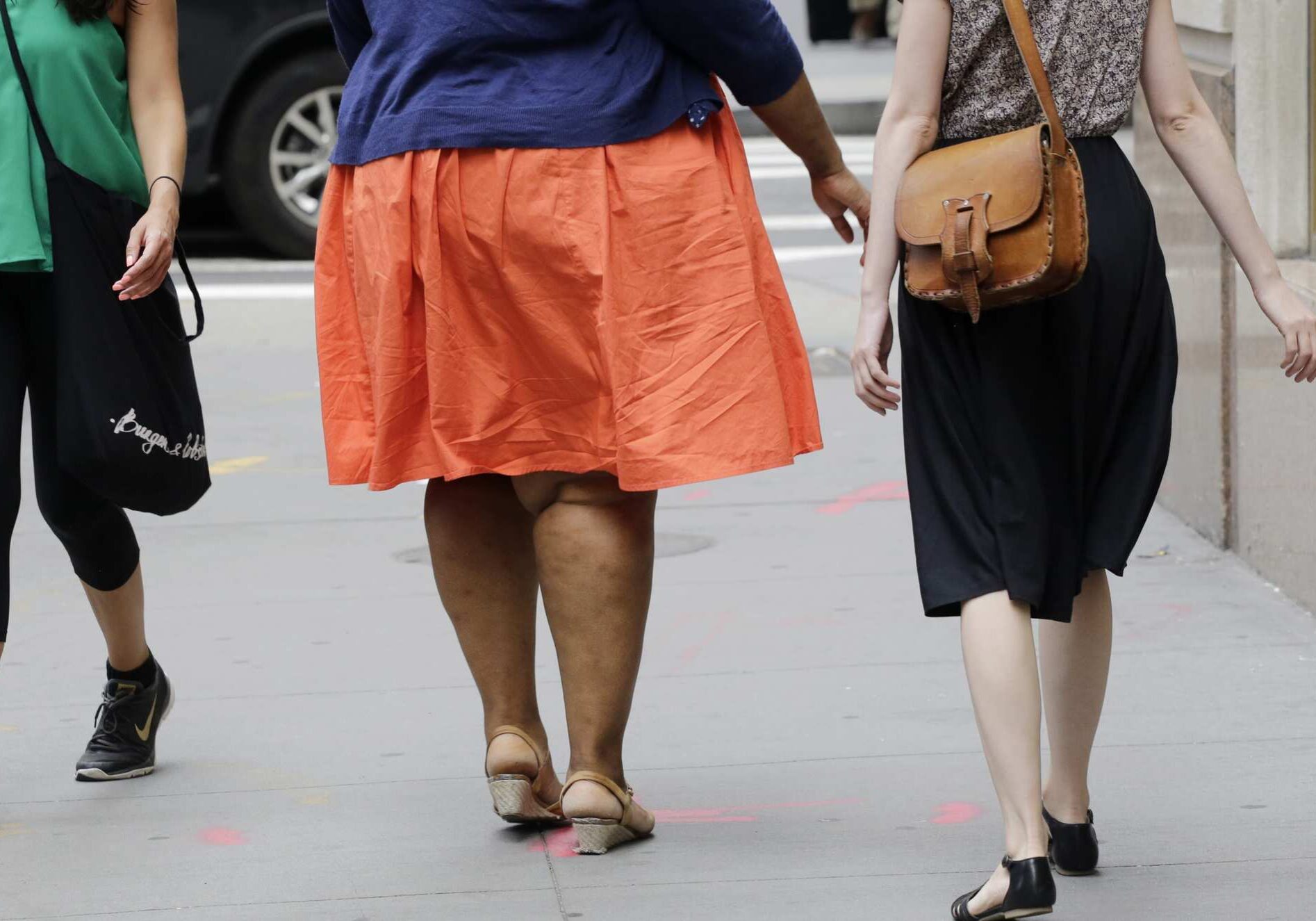 An obese woman, center, walks in New York, Monday, July 13, 2015. (AP Photo/Mark Lennihan)