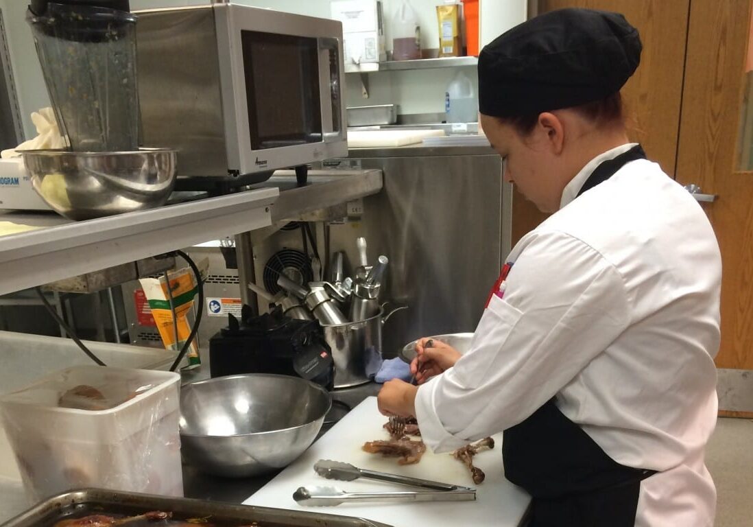 Senior Sarah Miller prepares the duck confit for Wednesday's opening night at Broadmoor Bistro. (photo by Caitlin Cress/The Hale Center for Journalism) 