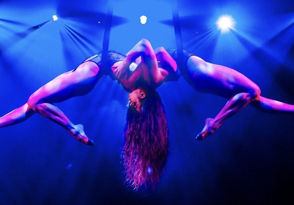 Two Quixotic performers dangle above the stage in pose.