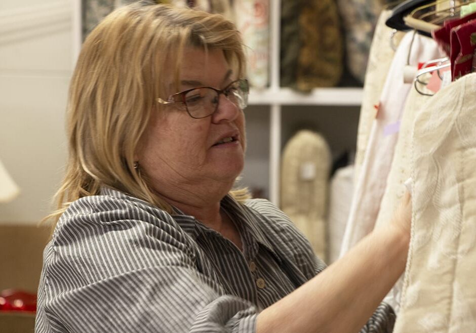 Sheryl Raineri arranges clothing at the Manor Thrift Shop in Liberty, Missouri.