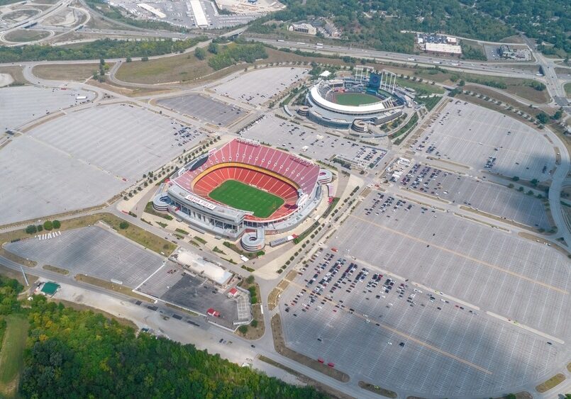 An aerial view of two stadiums with a large expanse of parking lot surroum.nding the