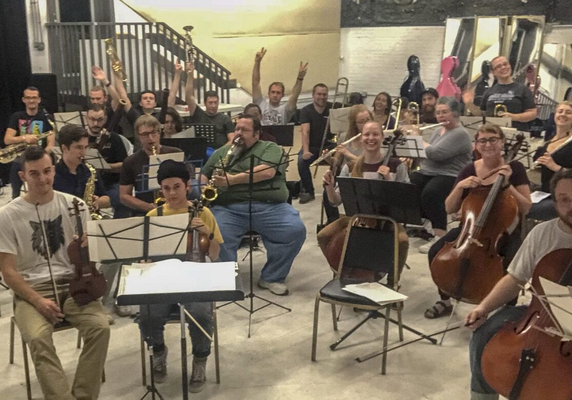 A crowd of musicians playing orchestral instruments.