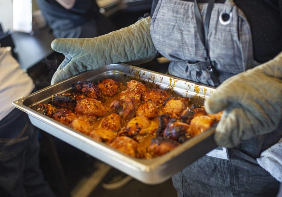 Program coordinator Sarah Tepikian brings out a chili-rubbed chicken special