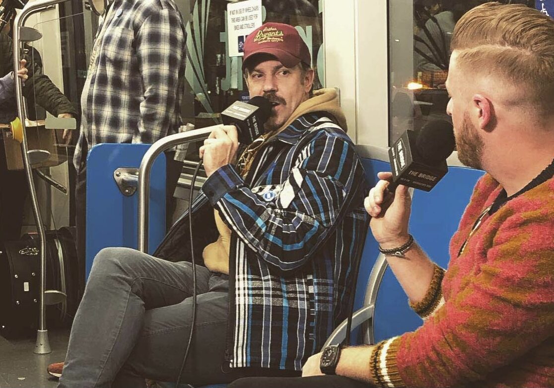 Jason Sudeikis speaks into a microphone aboard the KC streetcar.