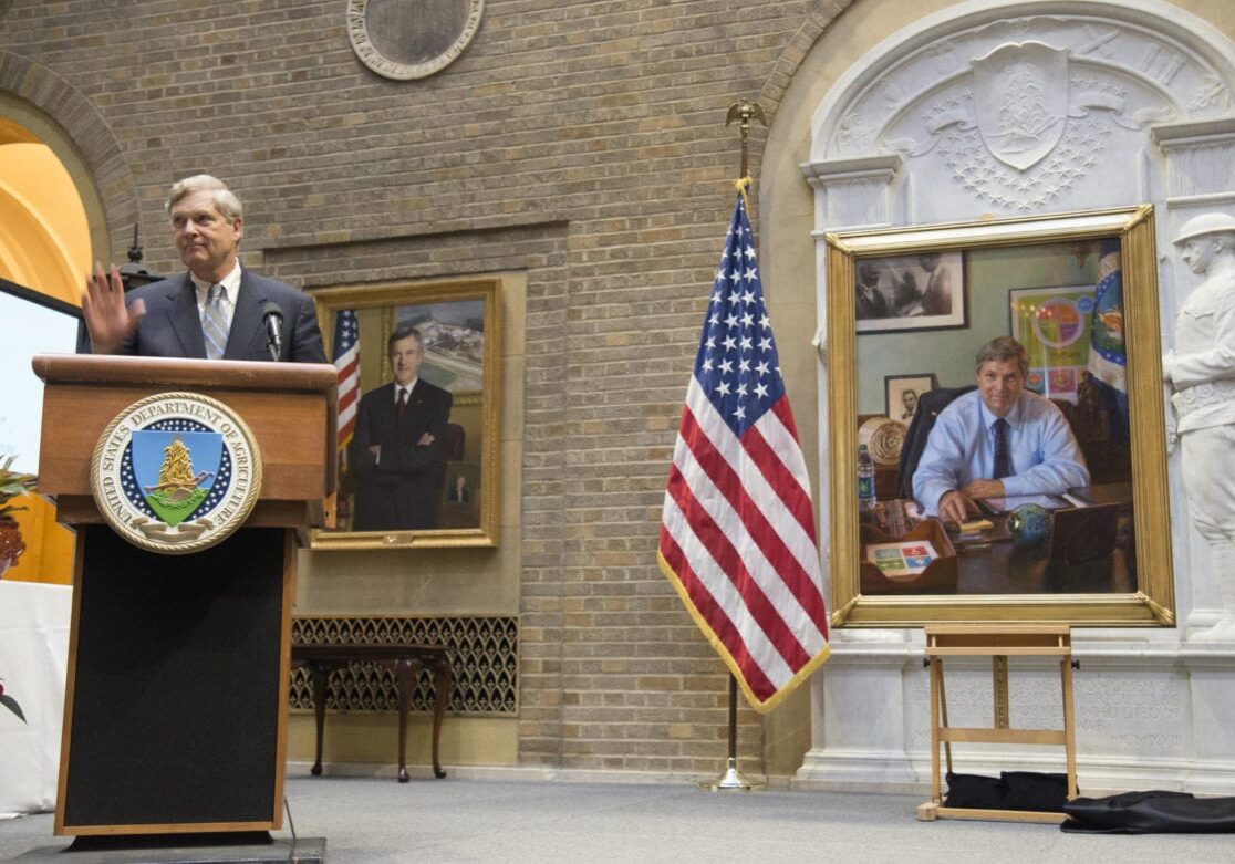 A man in a room with a portrait of himself.